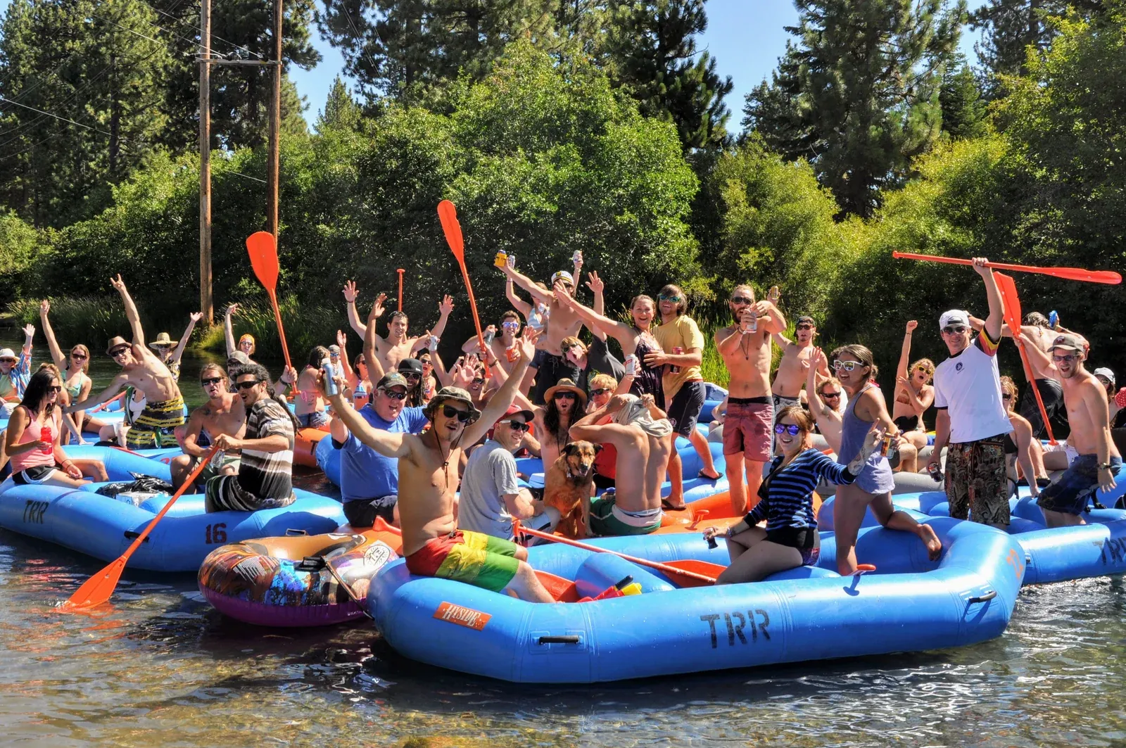 A group of rafters celebrating beside blue river boats