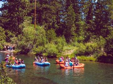 A line of rafters floating the Truckee River past tall pines