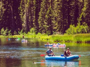 Two rafters drifting the Truckee River beneath a forested bank
