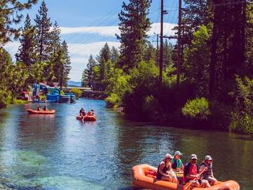 Guests floating down the Truckee River on orange paddles and blue rafts