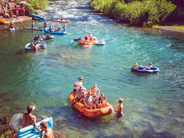 Guests swimming beside their raft in a Truckee River swimming hole