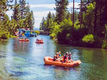 A raft of guests passing a forested stretch of the Truckee River