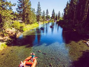An orange raft drifting the clear water of the Truckee River