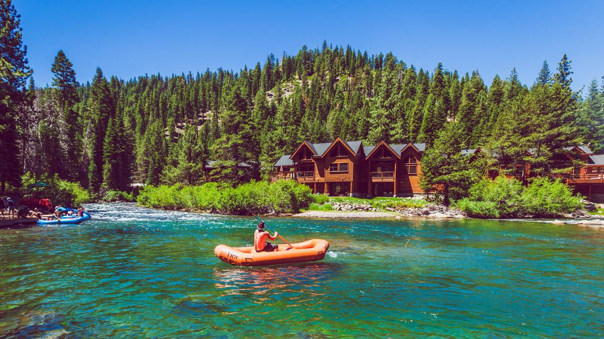 The Truckee River running clear and wide through pine forest below a mountain slope near Tahoe City