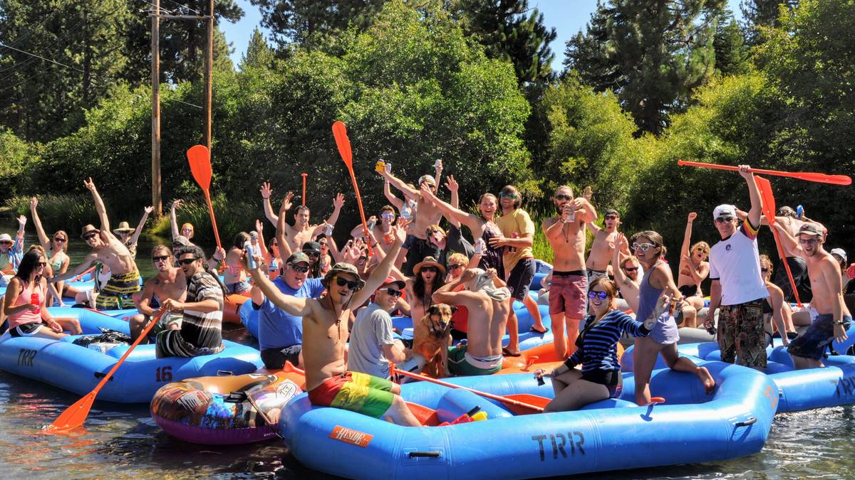 A large group of rafters on the Truckee River raising their orange paddles together