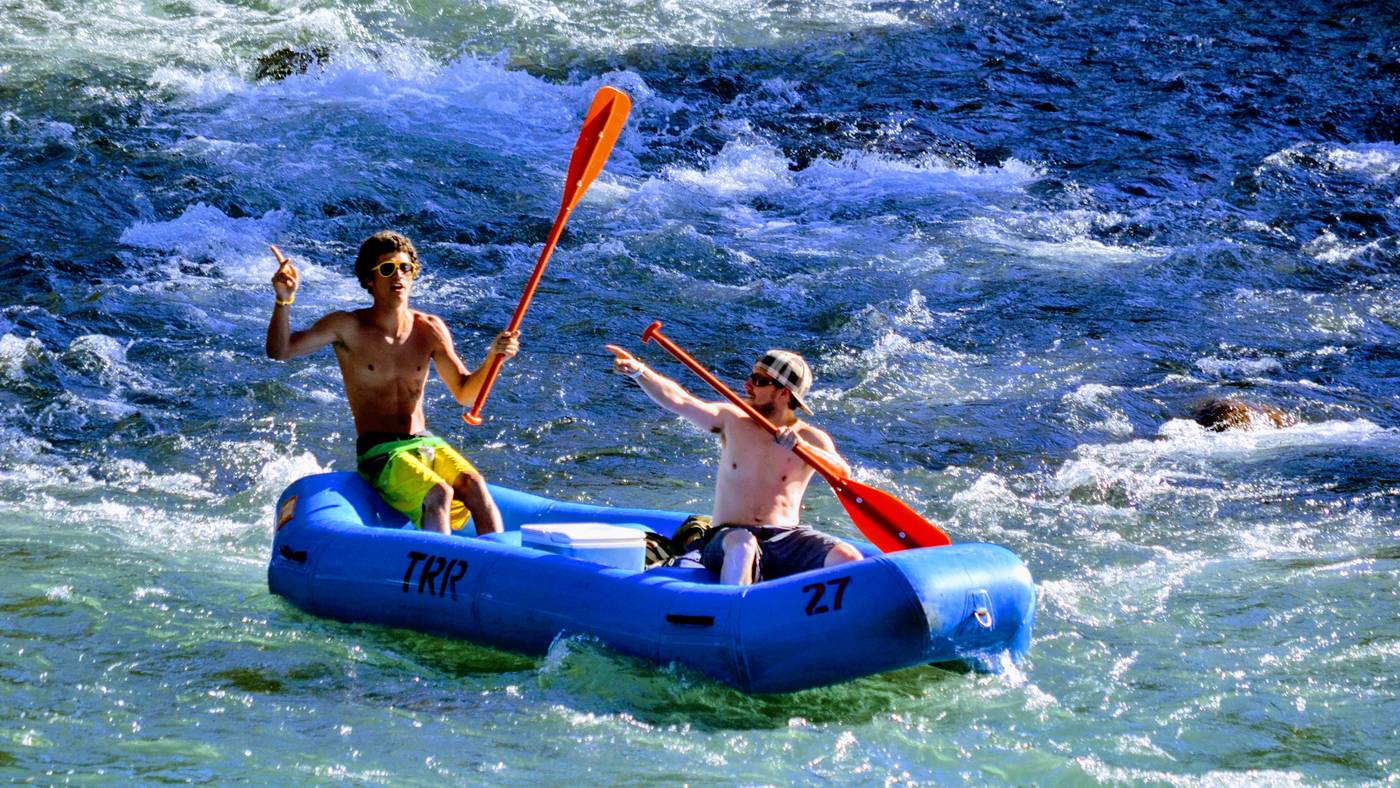 Two rafters paddling a blue raft through whitewater on the Truckee River in Tahoe City
